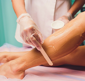 A professional cosmetologist performing hair removal treatment on a client in a spa setting.