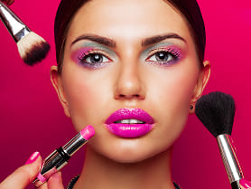 A professional makeup artist applying elegant makeup on a woman’s face in a well-lit studio.