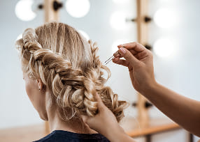 A woman showcasing a trendy, layered hairstyle with soft waves and highlights in a modern salon setting.