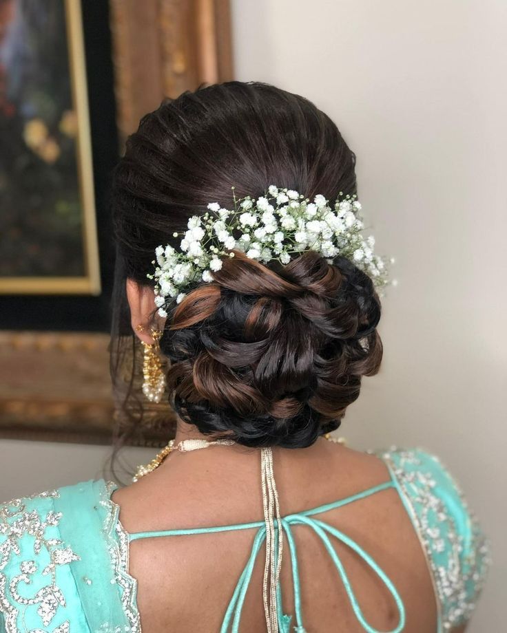 Elegant bridal hairstyle with intricate braids and floral accessories in a Dubai salon setting.