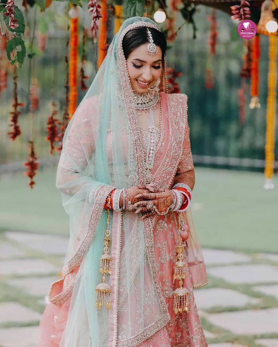 Indian bride wearing a traditional pink bridal dress with intricate embroidery and jewelry