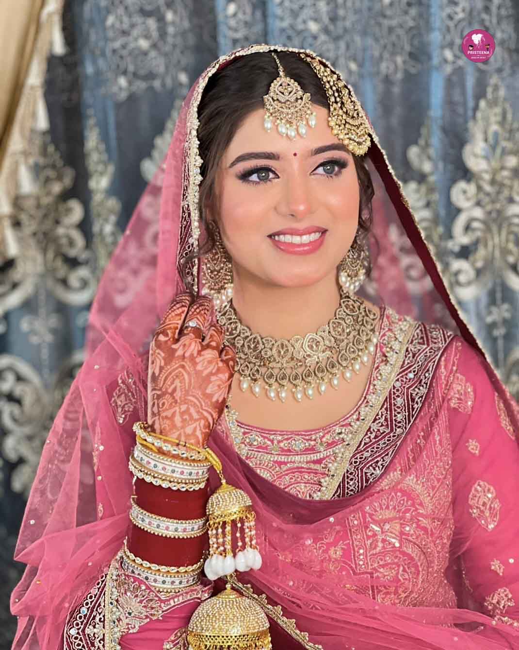 Indian makeup artist applying traditional bridal makeup with intricate detailing and vibrant colors.