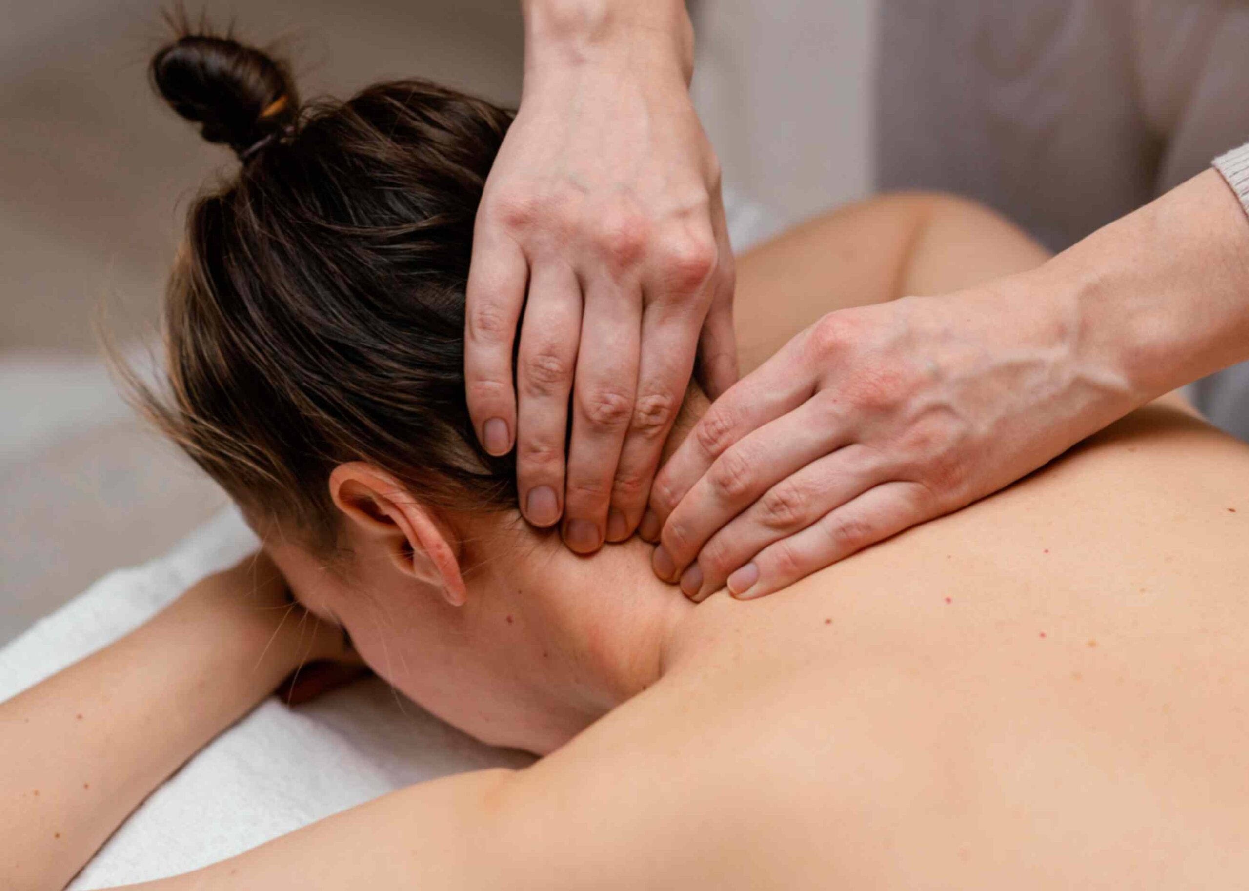a lady getting neck massage while lying on bed
